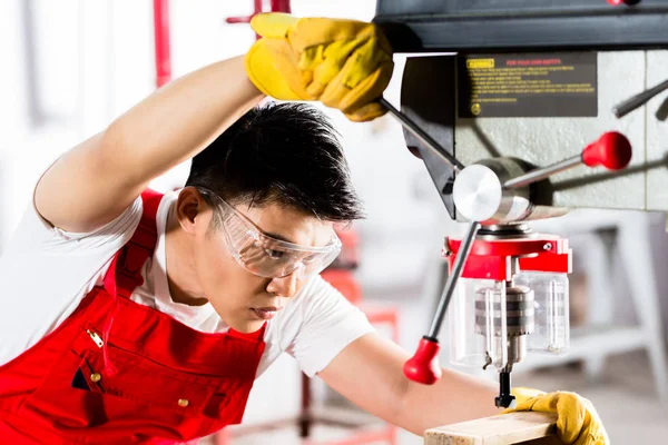 Hombre chino trabajando con taladro en fábrica —  Fotos de Stock