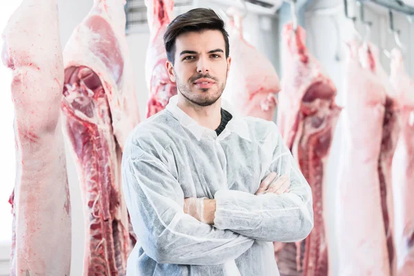 Arbeiter in Metzgerei steht vor Kadavern — Stockfoto