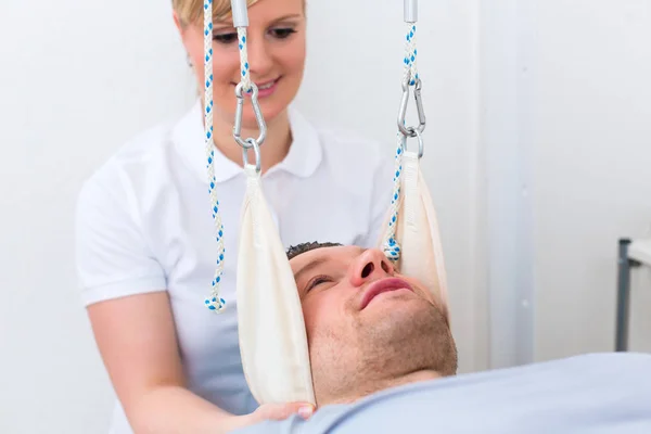 Physiotherapist exercising patient on sling table — Stock Photo, Image