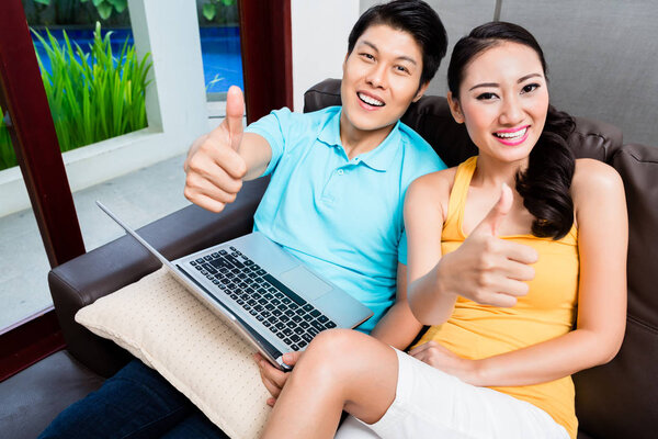 Азиатская женщина и мужчина серфинг показывая большие пальцы вверх
