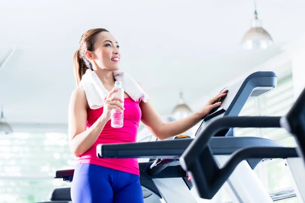 Smiling woman on treadmill presenting water bottle — Stock Photo, Image