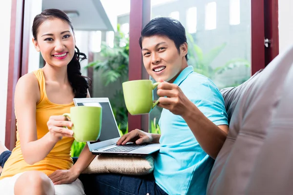 Chinesisches Paar surft auf Sofa und trinkt Kaffee — Stockfoto
