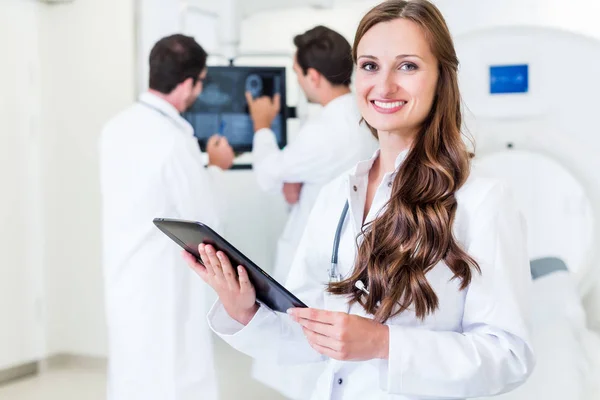 Doctor with colleagues standing in hospital at CT machine — Stock Photo, Image