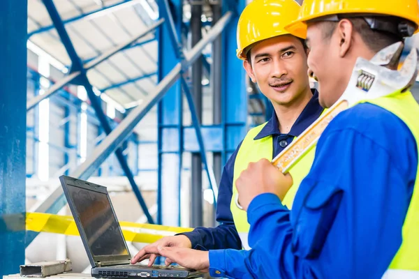 Arbeiter in Produktionsanlage mit Laptop lizenzfreie Stockfotos