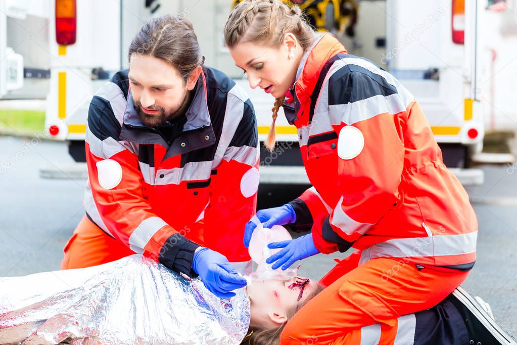 Ambulance doctor giving oxygen to female victim