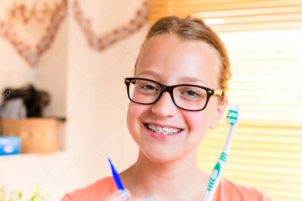 Teenager girl with dental braces brushing her teeth