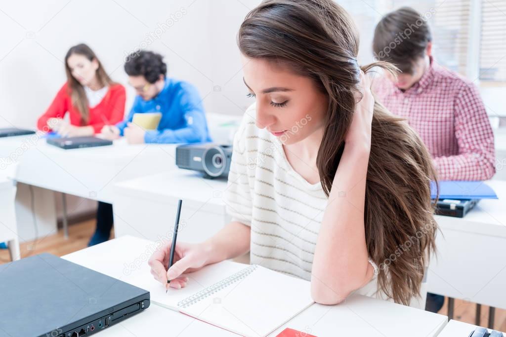 Student woman writing test in seminar room of university