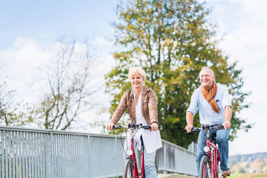 Senior couple with bicycles on bridge
