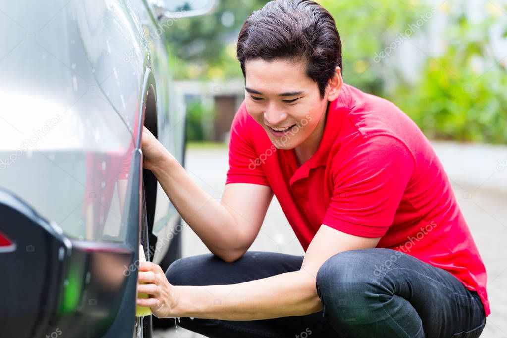 Asian man cleaning car rims