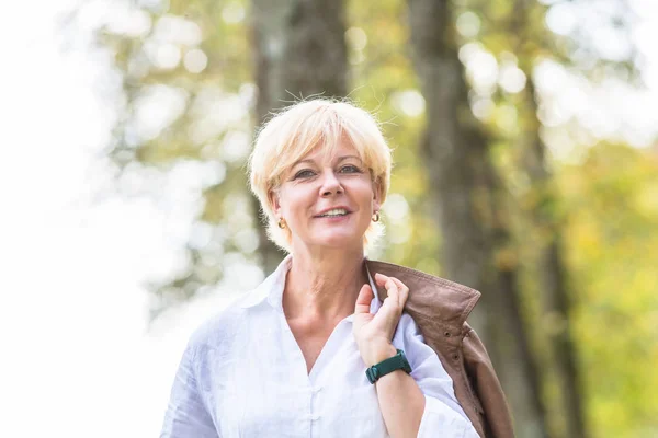 Senior Kvinna promenader i höst skog — Stockfoto