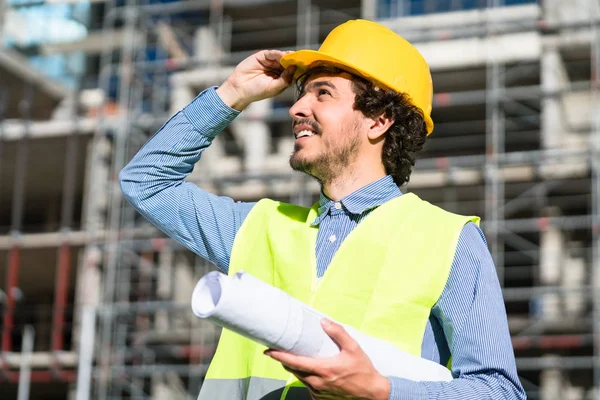 Architect studying floor plan at construction site — Stock Photo, Image