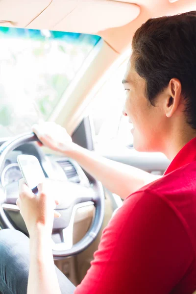 Ασιατική άνθρωπο μήνυμα γραπτών μηνυμάτων κατά την οδήγηση αυτοκινήτου — Φωτογραφία Αρχείου