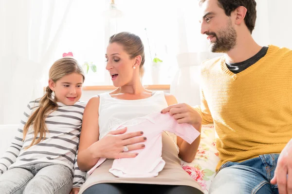 Família à espera de descendência e olhando para roupas de bebê — Fotografia de Stock