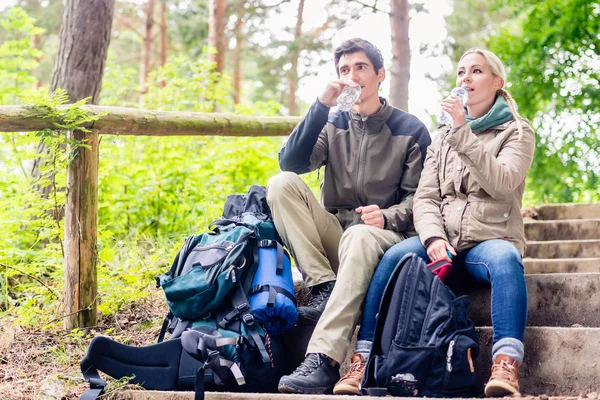 Rucksacktouristen ruhen sich aus und trinken Mineralwasser — Stockfoto