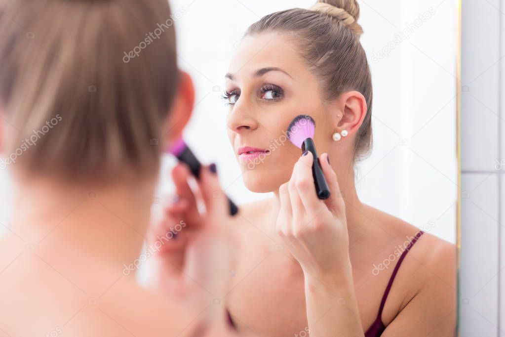 Woman powdering face with cosmetic brush 