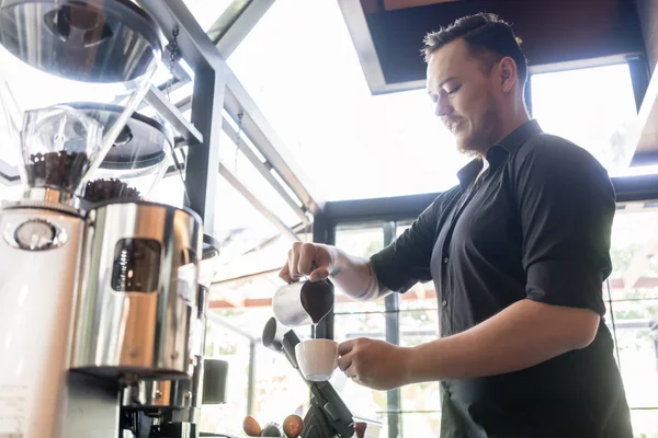 Barkeeper gießt Milch in Tasse Kaffee — Stockfoto