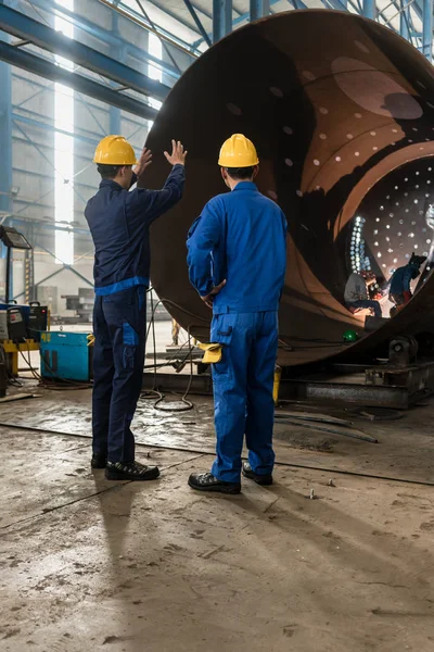 Trabajadores que supervisan la fabricación de cilindros metálicos — Foto de Stock