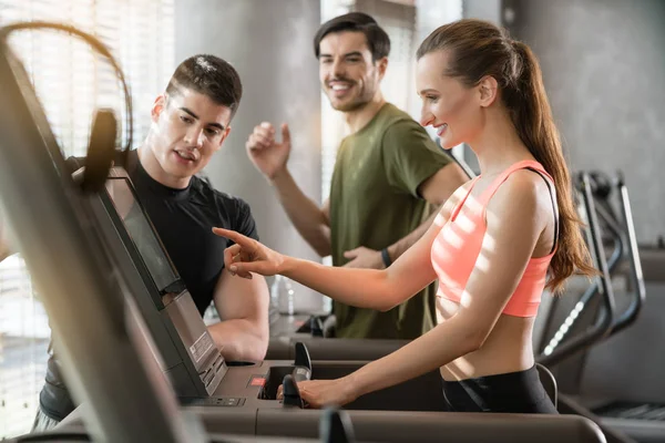 Young woman increasing speed of treadmill — Stock Photo, Image
