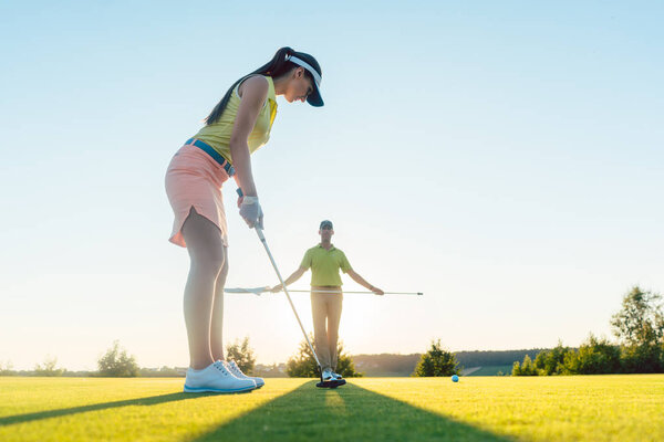 Low-angle side view of fit woman playing golf with partner