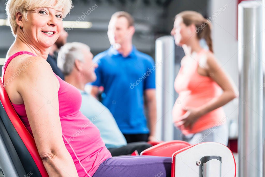 mature woman in group with pregnant woman working out at the gym 