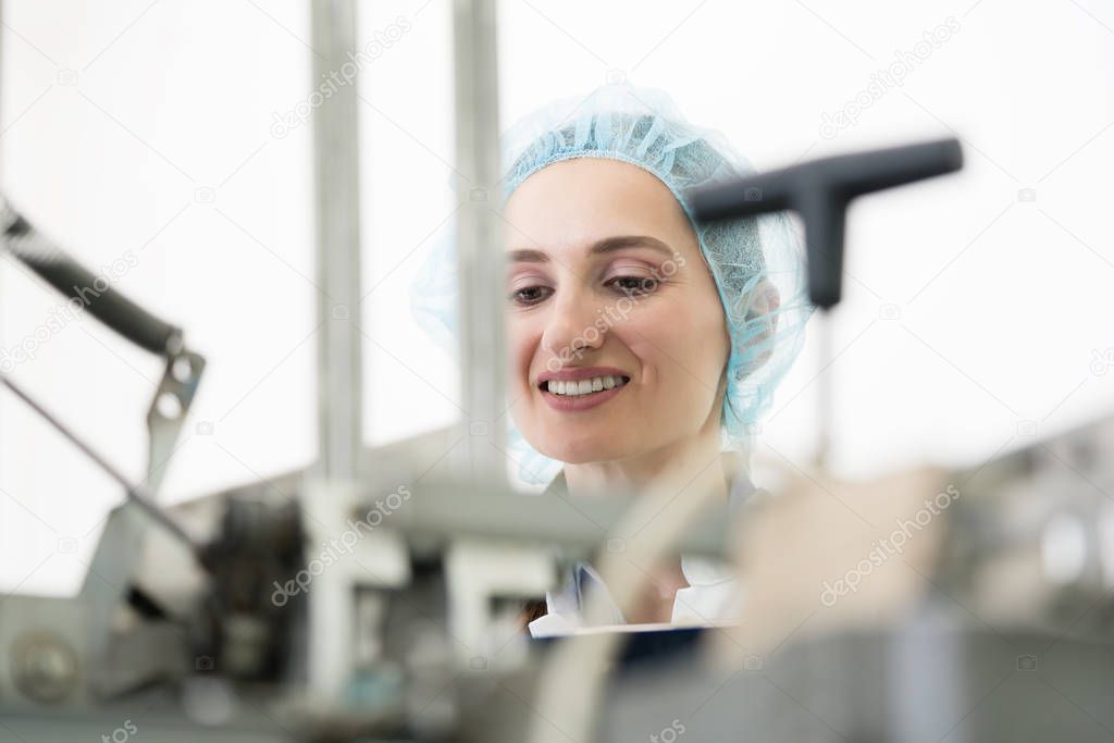 Portrait of smiling woman wearing protective headwear while checking equipment