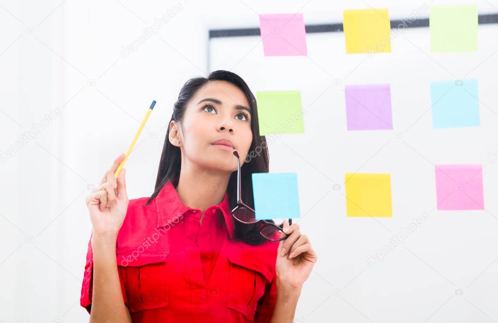 Portrait of young asian employee looking at multiple reminders 