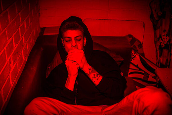 young man taking dangerous drugs orally while lying down on a couch 