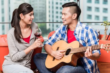 After moving together young man plays love song for his girlfrie clipart