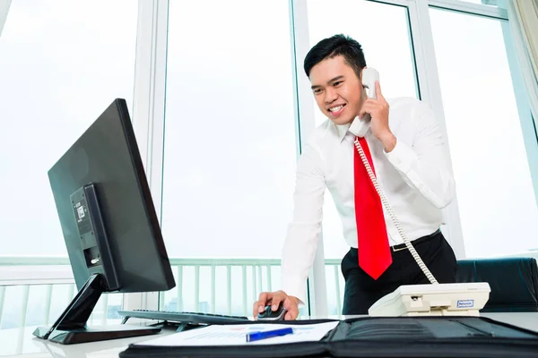 Asian businessman  on phone working in office — Stock Photo, Image