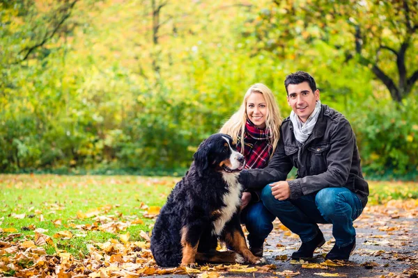 Par med hund som njuter av hösten i naturen — Stockfoto