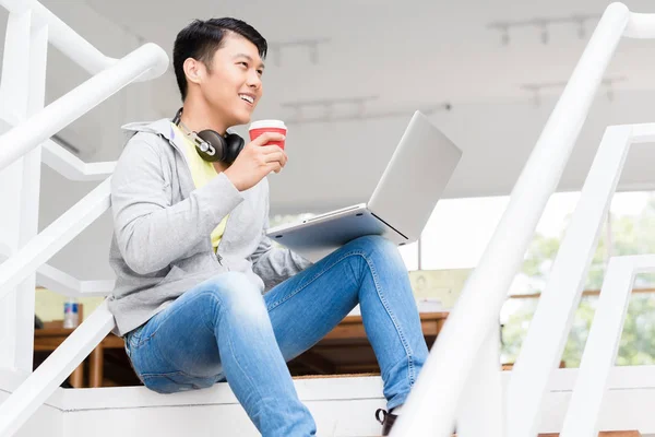 Heureux jeune employé asiatique en utilisant un ordinateur portable dans un bureau moderne — Photo