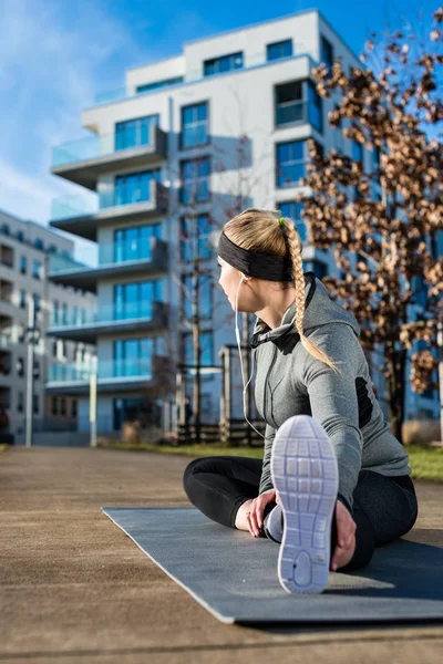 Ajuste mujer joven estirando su pierna durante el calentamiento al aire libre exerci — Foto de Stock