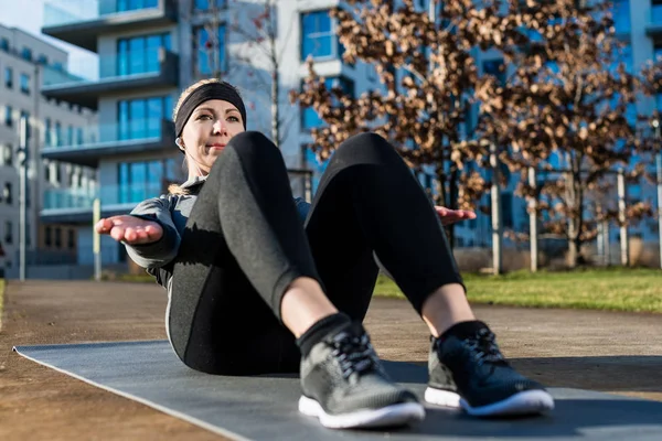 Genç kadının abdomina için yukarı yükseltilmiş avuç içi mekik yapması