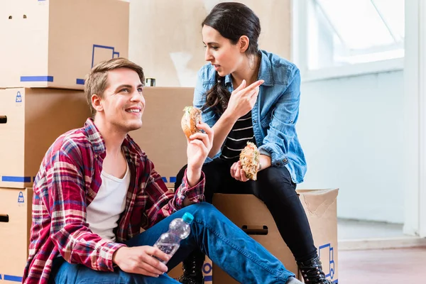 Junges Paar sieht müde aus, während es in der Pause ein Sandwich isst — Stockfoto