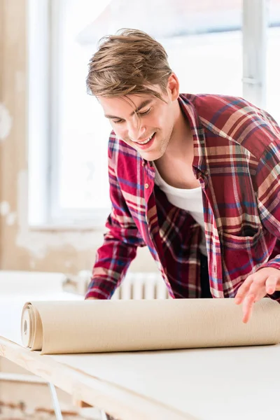 Jovem aplicando colar para a superfície de uma folha de papel de parede dur — Fotografia de Stock