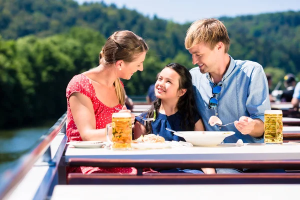 Family at lunch on river cruise with beer glasses on deck Royalty Free Stock Images
