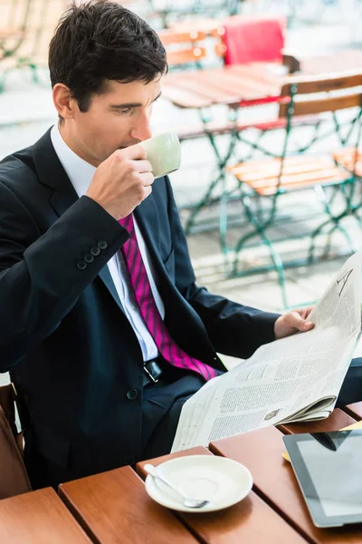 Affärsman läsa en tidning och dricka kaffe i morgonen — Stockfoto