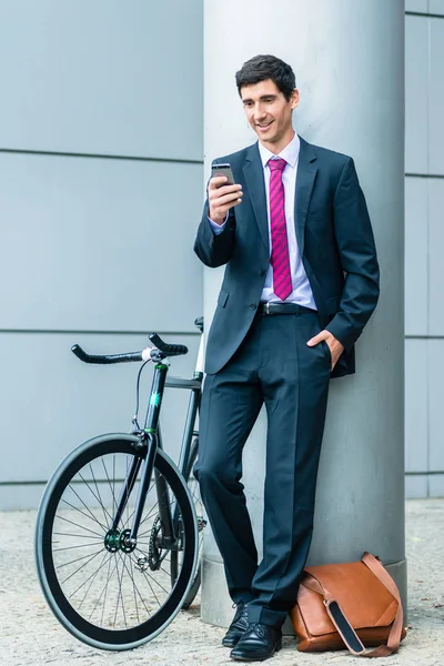 Jovem alegre se comunicando no telefone celular enquanto espera o — Fotografia de Stock