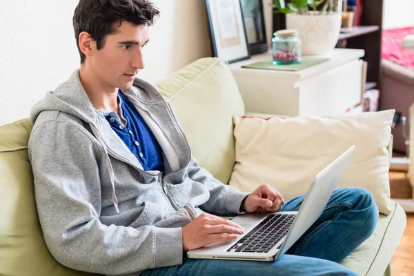 Giovane bell'uomo che naviga in internet sul computer portatile a casa — Foto Stock