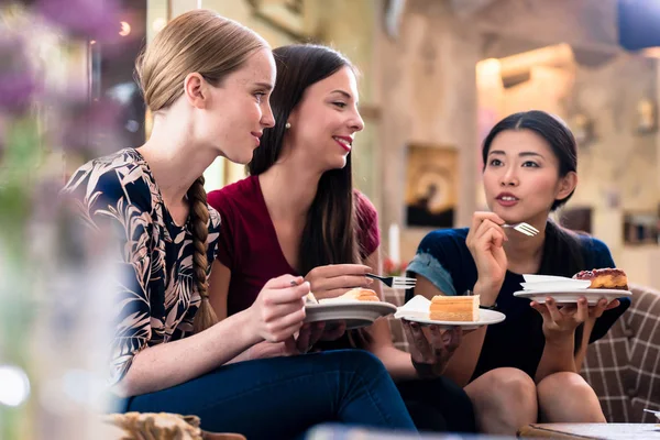 Három fiatal nők eszik süteményt beltéri — Stock Fotó