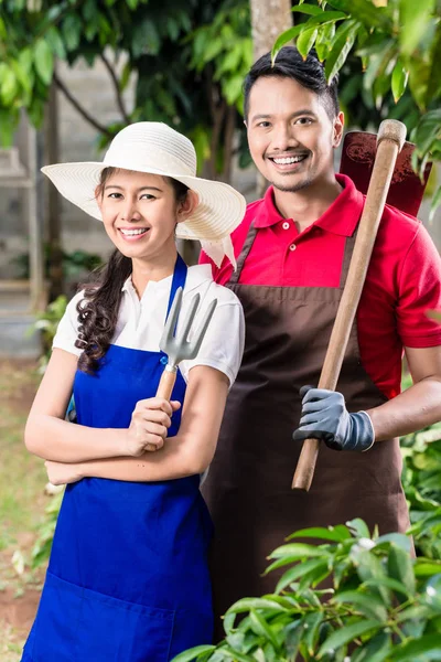 Giovane coppia asiatica sorridente mentre lavora in giardino — Foto Stock