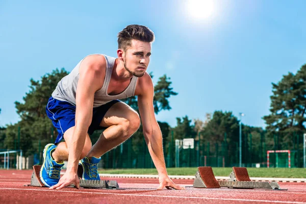 Track and field sprinter on starting point at cinder track in sp — Stock Photo, Image