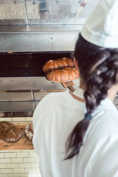 Panadero conseguir pan fresco con pala fuera del horno — Foto de Stock