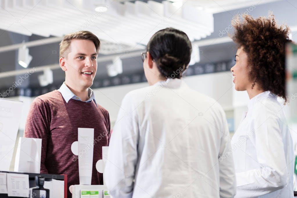 Happy customer talking with two helpful pharmacists in a contemp