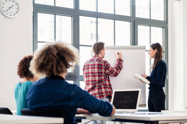 Student writing on a training paper board while presenting with