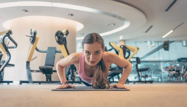 Mujer haciendo push-up en el gimnasio para una mejor aptitud —  Fotos de Stock