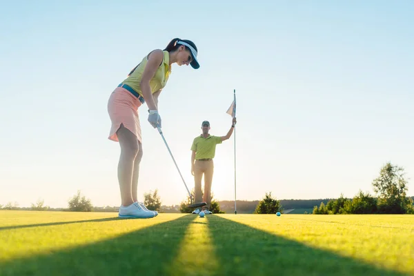 Passar kvinna utövar slår teknik under golf klass med en — Stockfoto