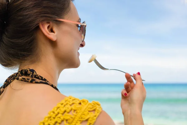 Женщина на тропическом пляже ест банан у моря — стоковое фото