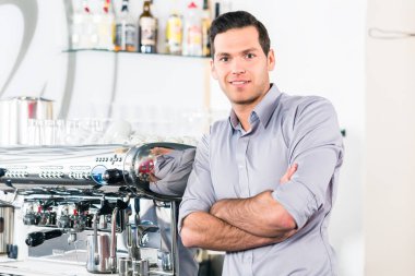 Genç adam bir modern otomatik kahve makinesi poz