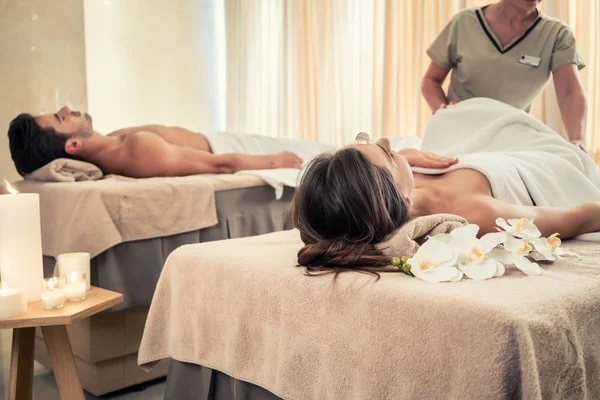 Young couple lying down on massage beds during crystal therapy